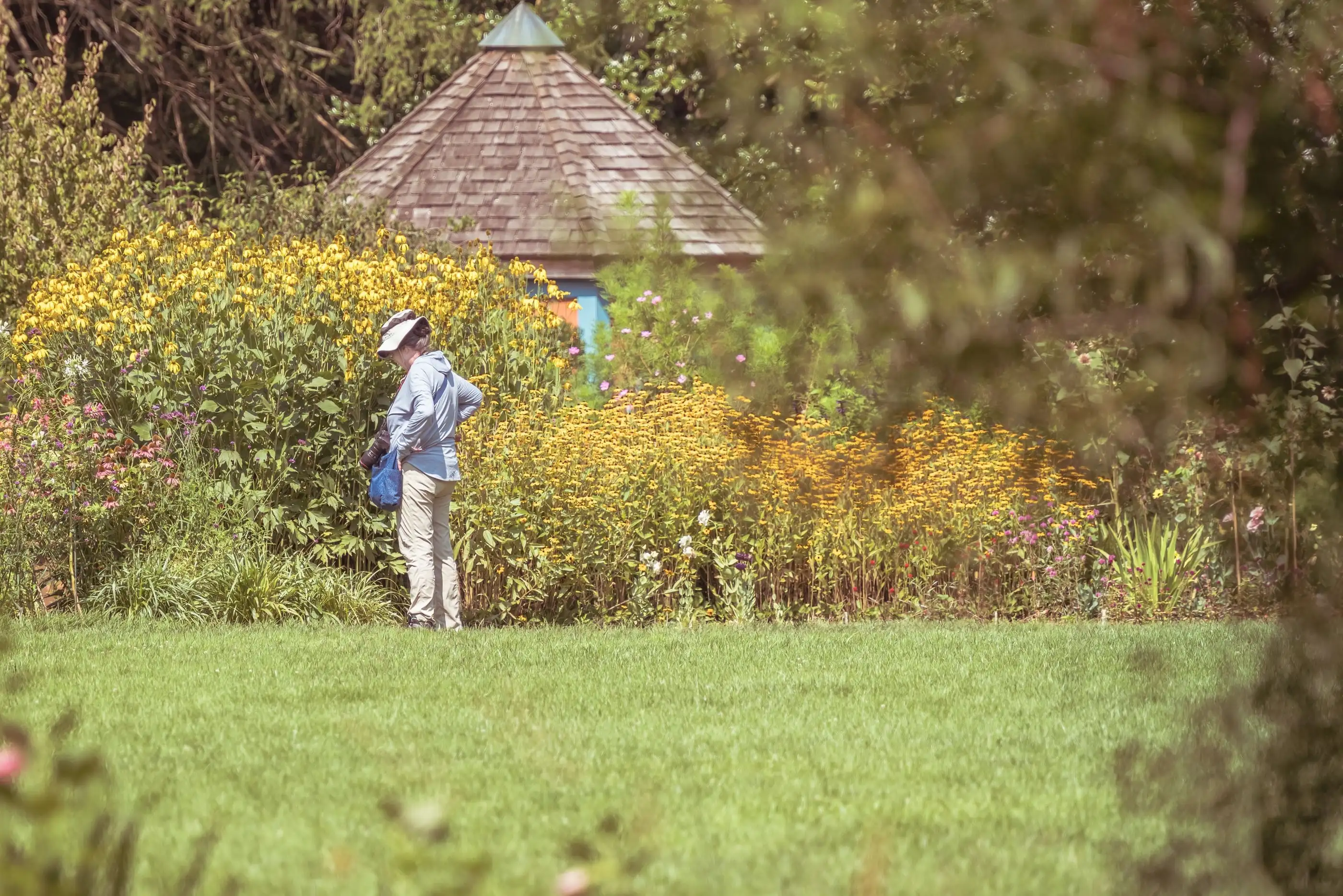 Jardinière de dos qui photographie des massifs fleuris pour le rapport de passage.